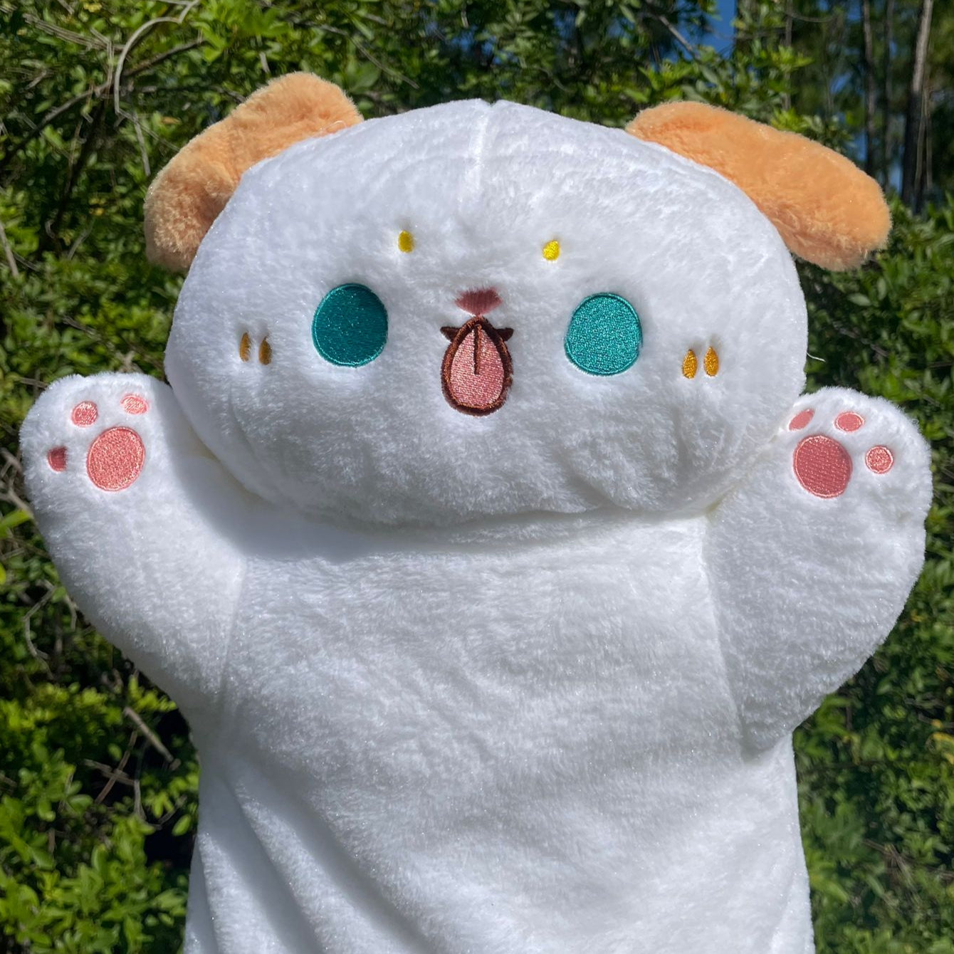 Plush toy with a happy expression in front of green foliage