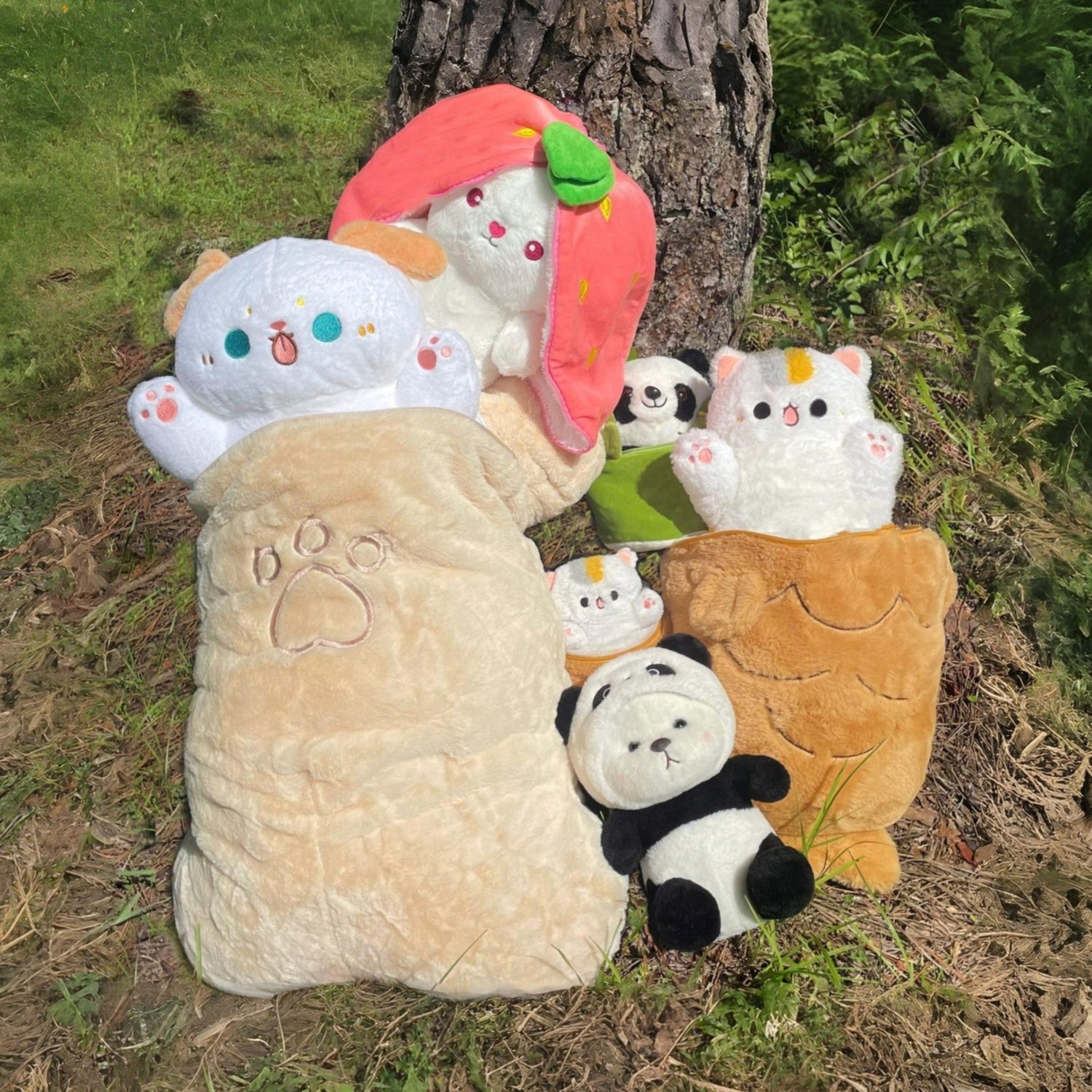 Plush toys leaning against a tree trunk outdoors.